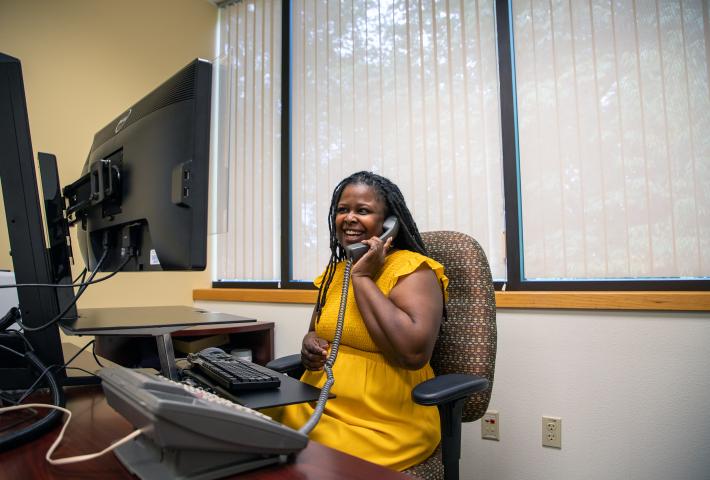 Black woman sitting at desk on the phone