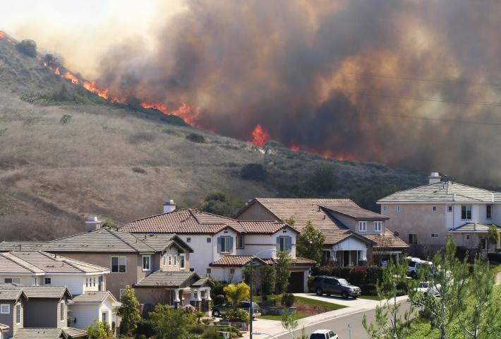 Wildfire on hill above homes. 