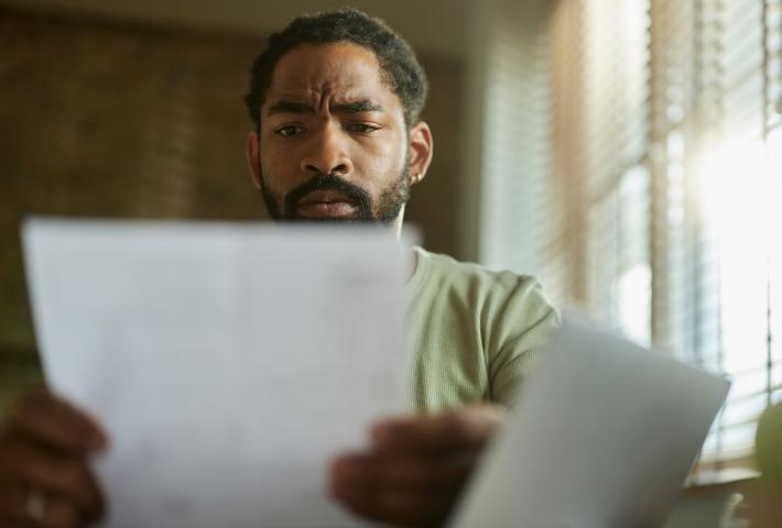 Black man looking at paper in home office