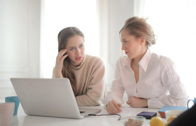 a women helping another women at a computer